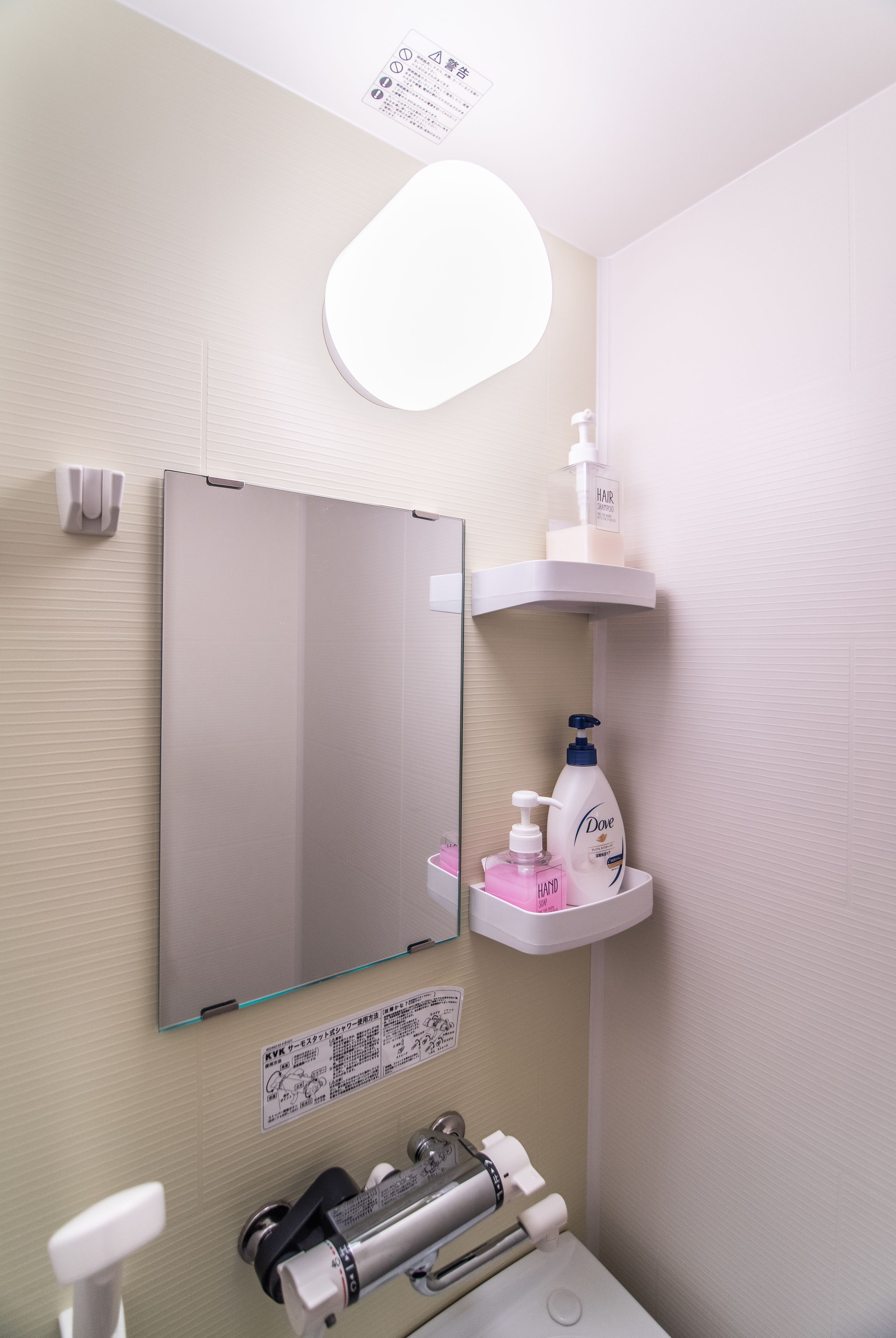 A bathroom with a large mirror, a sink, a toilet, and a shelf with toiletries.