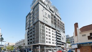 Ein mehrstöckiges Hotel mit modernem Design, das einen markanten Eingang und eine Dachterrasse bietet.