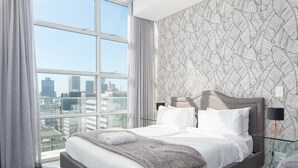 Ein modernes Hotelzimmer mit einem großen Bett, Blick auf die Stadt und einer Wand mit Muster.