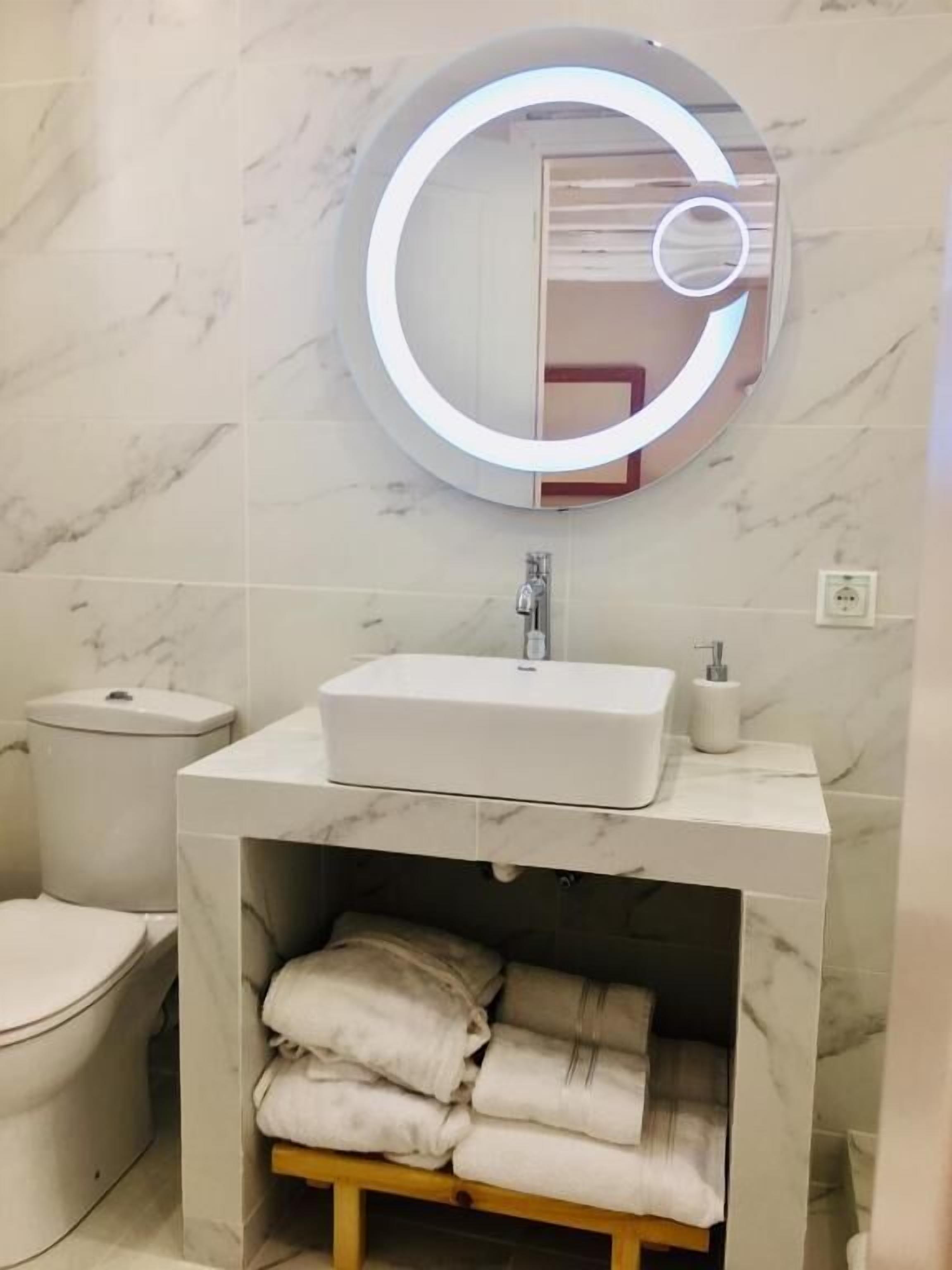 A bathroom with a marble vanity, a toilet, and a towel rack.