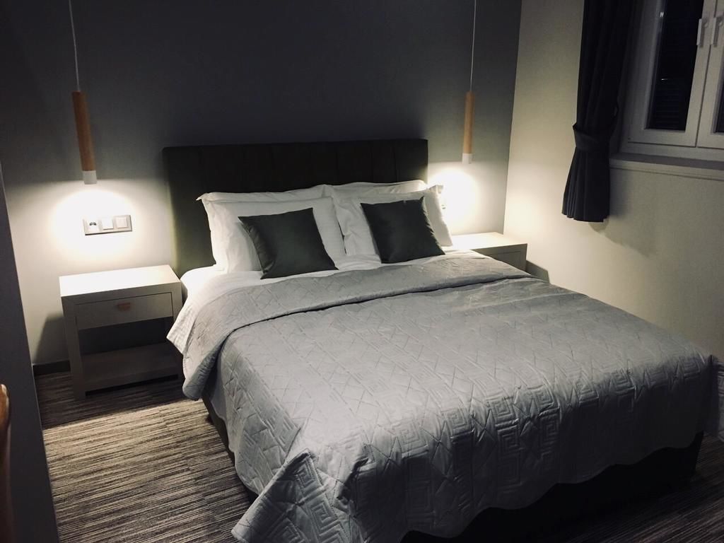 A neatly made bed with a grey quilt, two bedside tables with lamps, and a dark headboard.