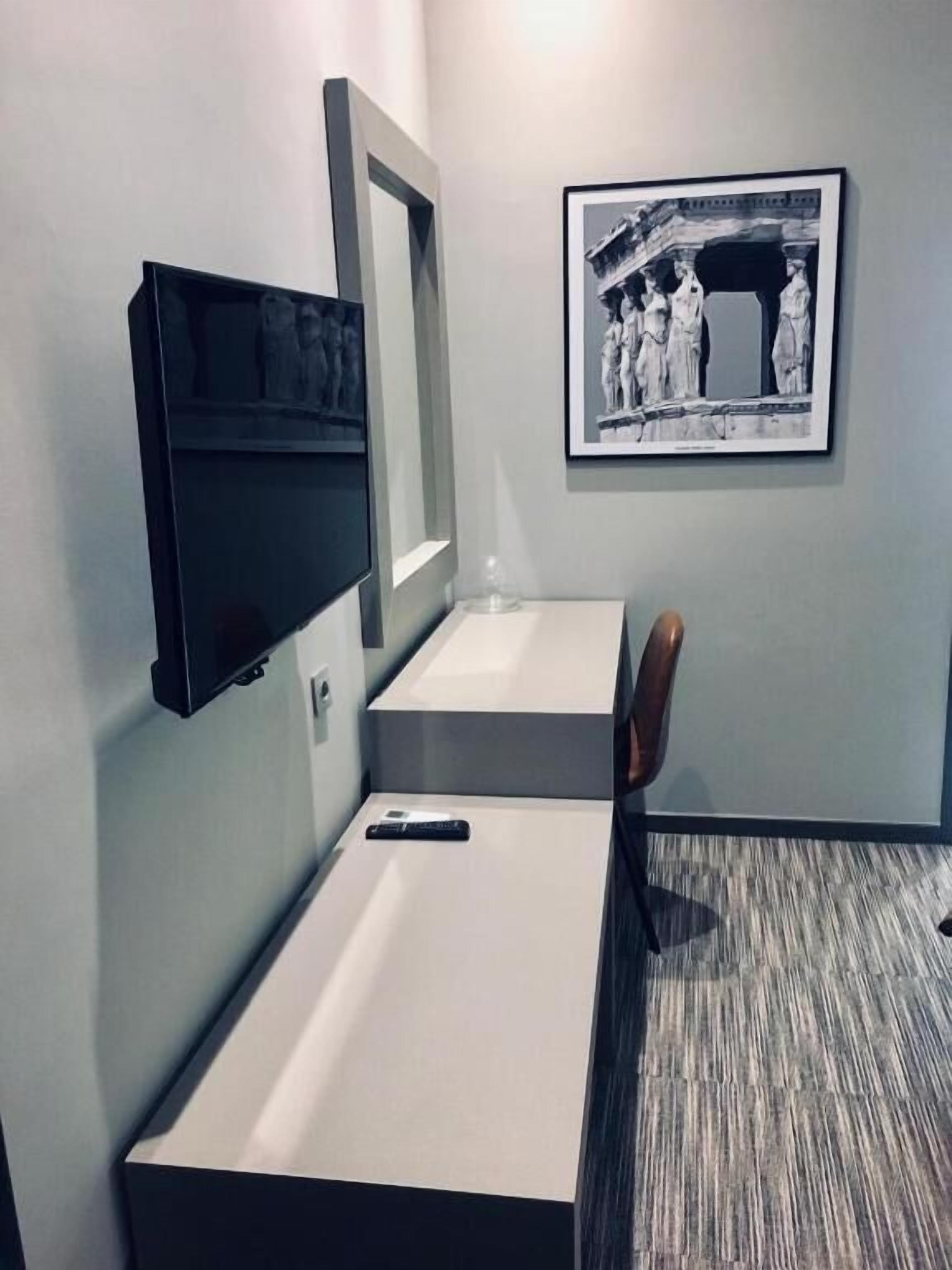 A modern bathroom with a built-in sink, a mirror, and a framed black and white photograph on the wall.
