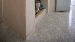 A kitchen with a sink, a refrigerator, and two shelves with kitchenware. - Pasithei Studios (Santorini)