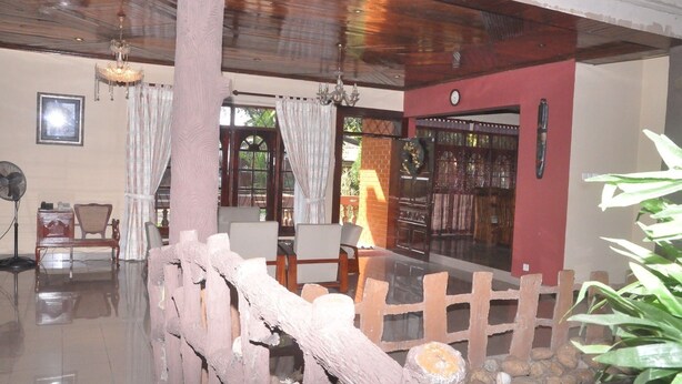 A room with a wooden ceiling, a wooden fence, a dining table with chairs, and a window with curtains. - Casual Stay Villa (Negombo)