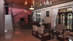 A spacious living room with a staircase, wooden ceiling, and large windows with curtains. - Casual Stay Villa (Negombo)