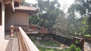 A balcony with a wooden railing, a small garden area with a gazebo, and a pathway leading to a brick wall. - Casual Stay Villa (Negombo)