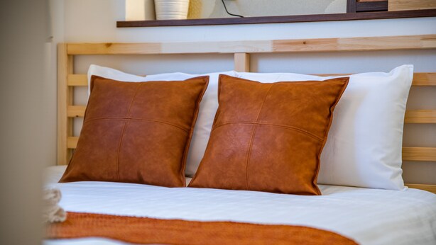 A neatly made bed with two brown pillows and a white blanket. - Kujira 203 (Osaka)