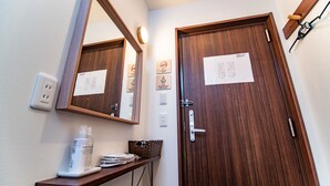 A bathroom with a wooden door, a mirror, a shelf with toiletries, and a paper on the door. - Kujira 203 (Osaka)