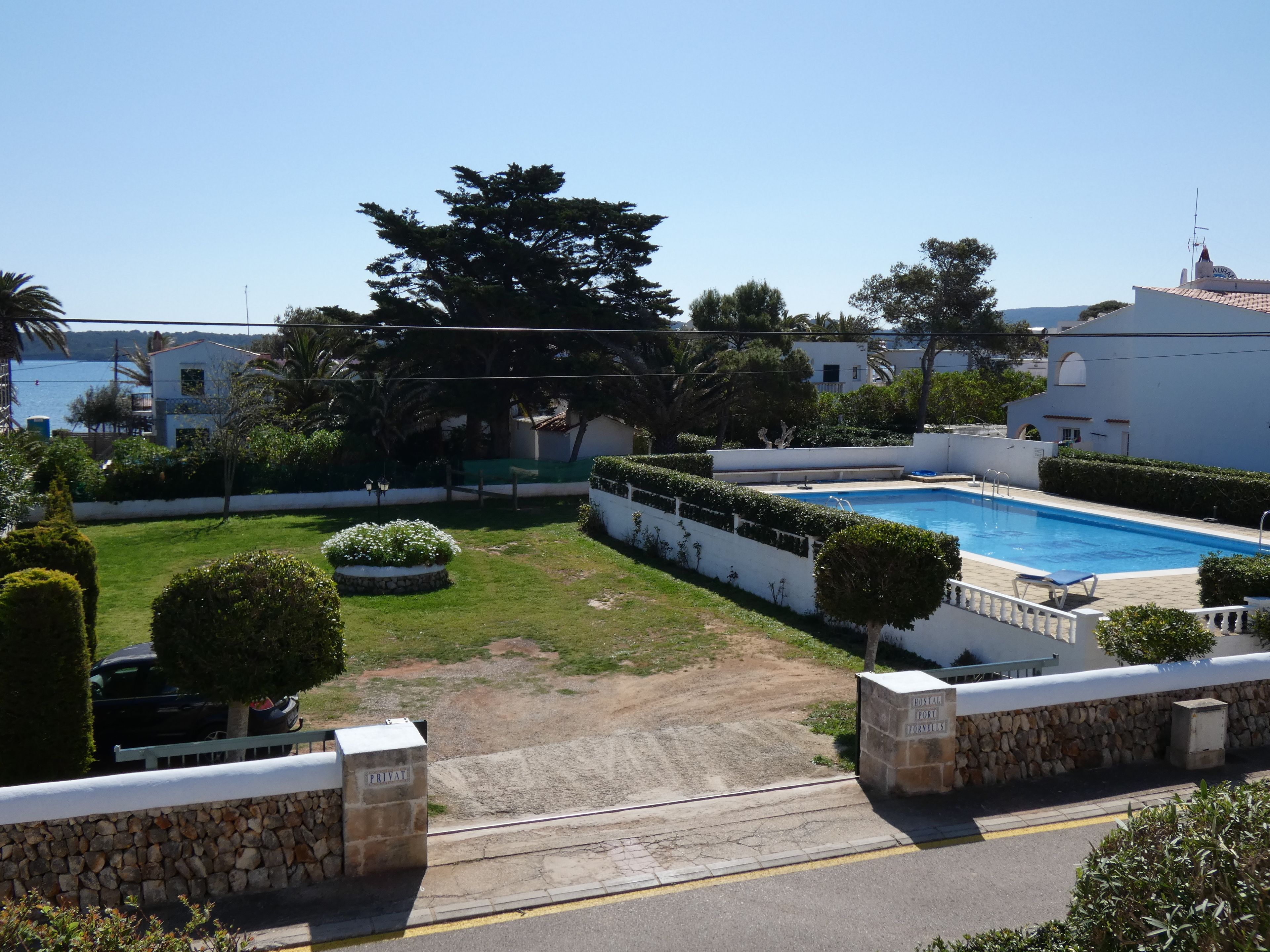 A private pool area with a stone wall, a paved walkway, and a view of the sea.