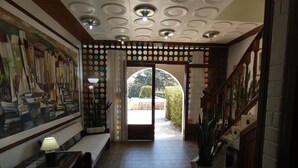 A lobby with a mural, a staircase, and a view of the outside. - Hostal Port Fornells - Adults Only (Mercadal)