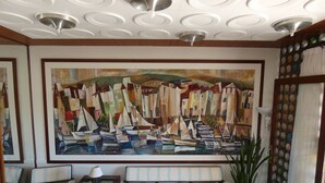A room with a large abstract painting, a sofa, a table, and a potted plant. - Hostal Port Fornells - Adults Only (Mercadal)