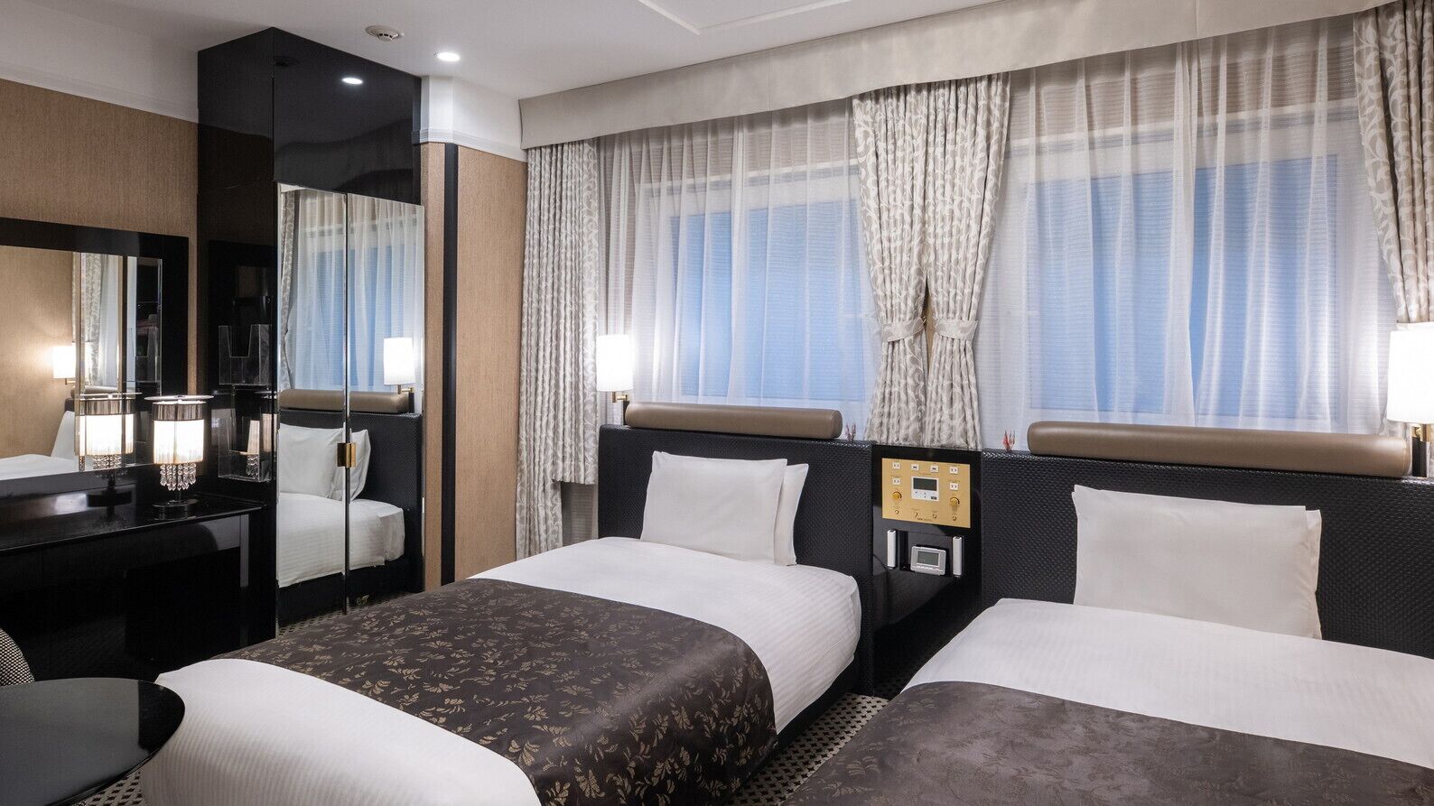 Ein Hotelzimmer mit zwei Betten, einem Schreibtisch, einem Spiegel und einer Bedienkonsole.