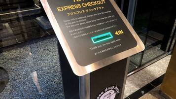 A sign for an express checkout area with instructions in English and Japanese, a green light indicator, and a 'Please drop here' sticker.