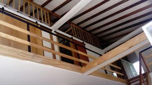 Eine mehrstöckige Holzkonstruktion mit Balkon, weißen Wänden und einer sichtbaren Treppe.