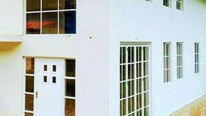 Ein zweistöckiges Gebäude mit weißer Fassade, zahlreichen Fenstern und einem Holzdach.