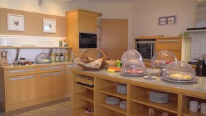 A well-equipped kitchen with wooden cabinets, a microwave, and a coffee machine. - Landhotel Larenzen (Kirchham)