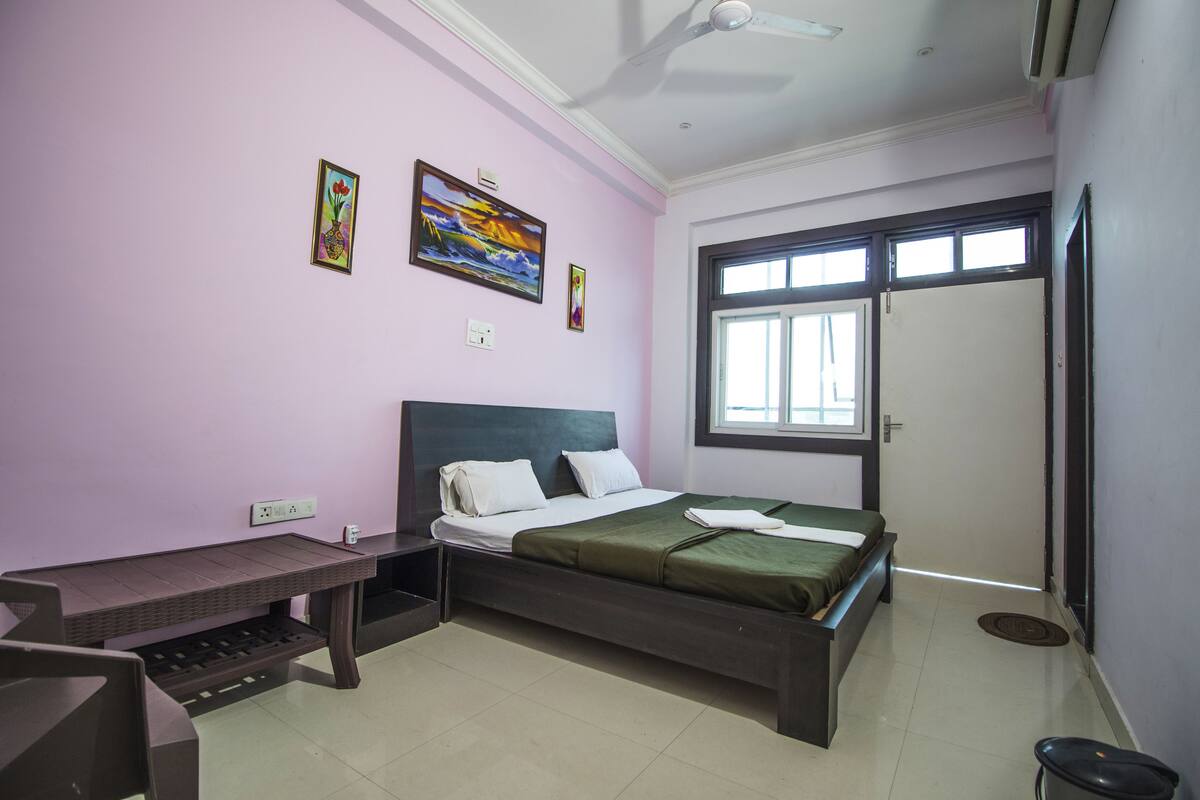 A bedroom with a bed, a desk, and a window.
