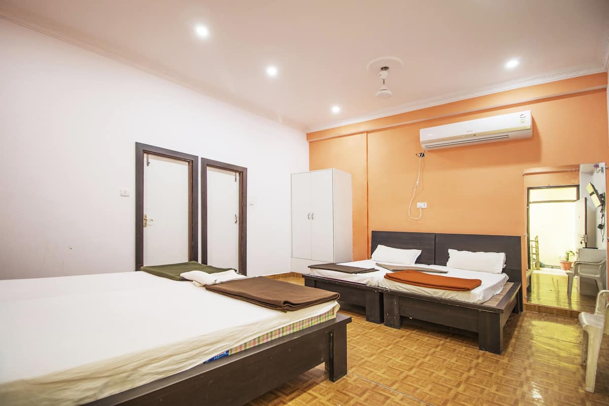 A hotel room with two beds, a wardrobe, an air conditioning unit, and a mirror.