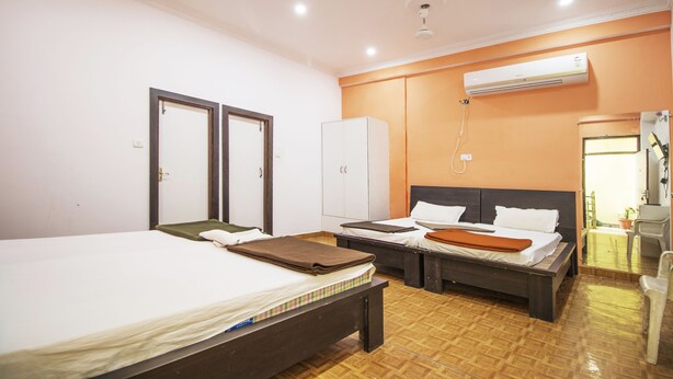 A hotel room with two beds, a wardrobe, an air conditioning unit, and a mirror. - Hotel Rudra (Majhgawan)
