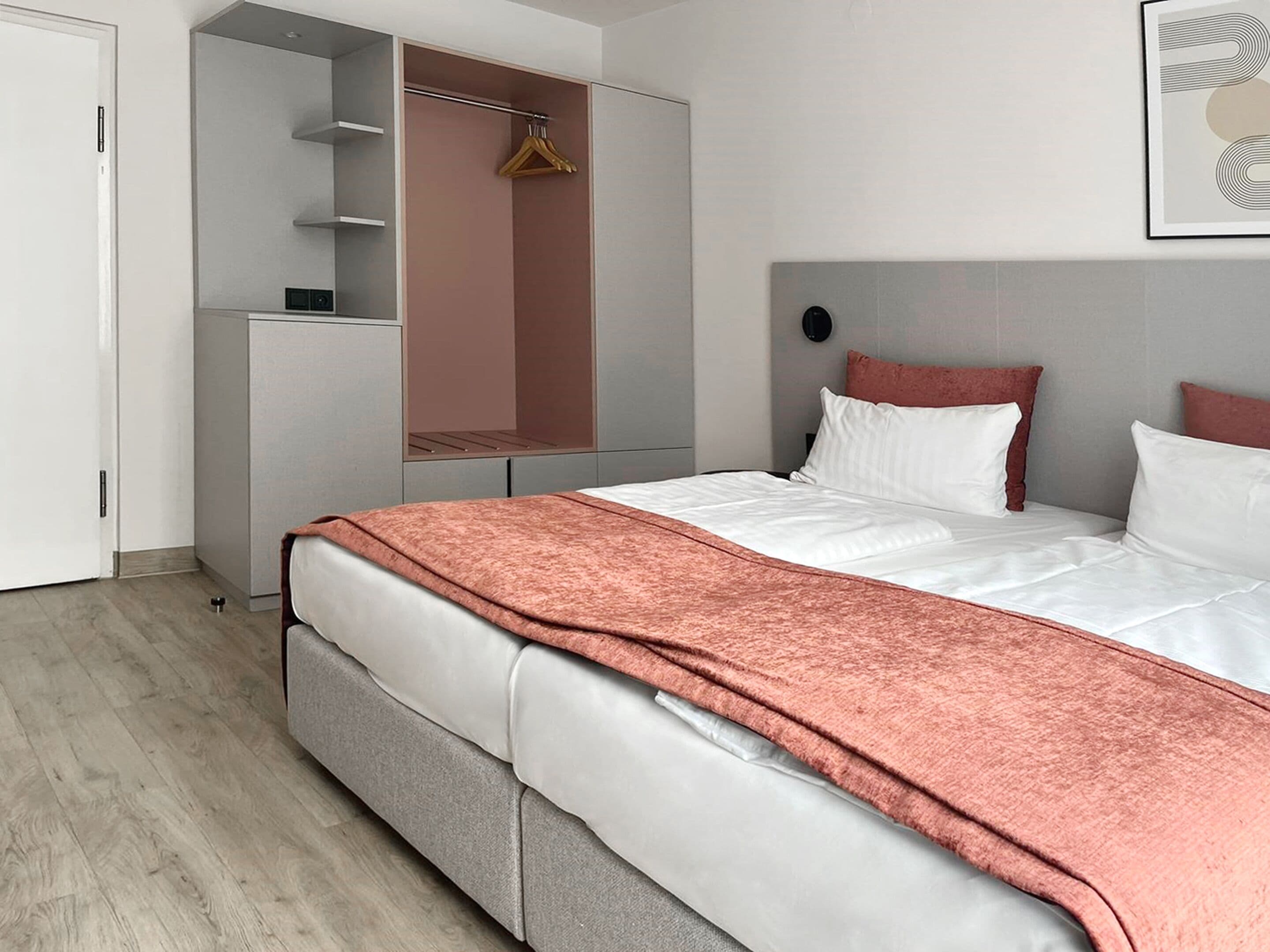 A modern bedroom with a bed, a wardrobe, and a hanging space.