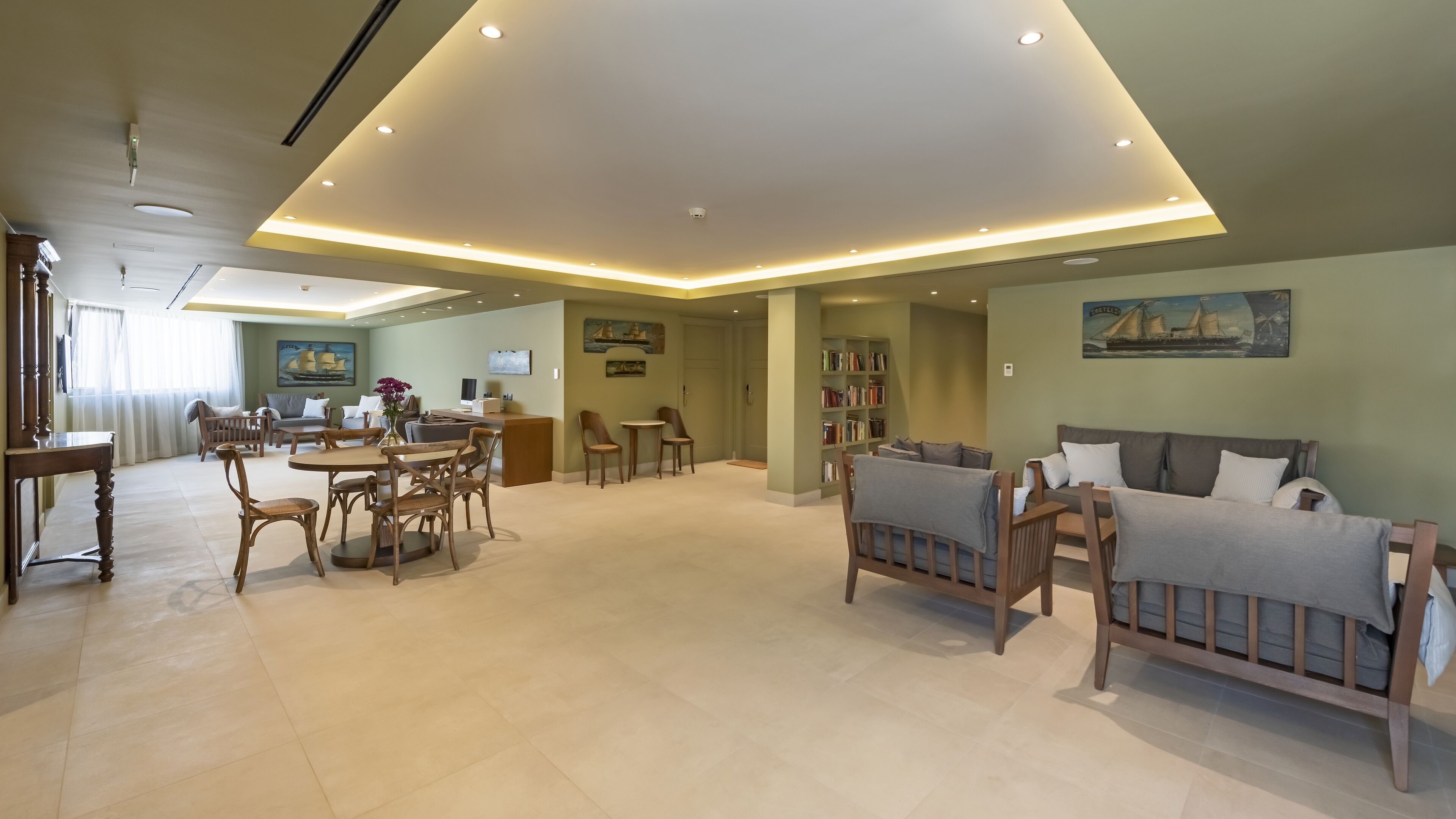 A spacious living area with a dining table, sofas, and a bookshelf.