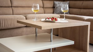 A modern living room with a beige sofa, a wooden coffee table with two glasses of white wine, and a plate of strawberries. - Apartmani Ralux Tivat (Tivat)