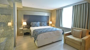 A modern hotel room with a large bed, bedside lamps, a sofa, and a view of the outdoors. - Adamel Hotel Istanbul (Istanbul)