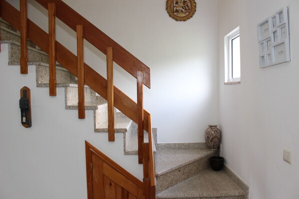 A staircase with wooden handrails, a small window, and a decorative wall piece. - House with fantastic views of the Serra do Gerês (Gerês)