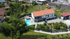 Ein modernes, zweistöckiges Haus mit Swimmingpool, umgeben von Grünflächen und weiteren Wohngebäuden.