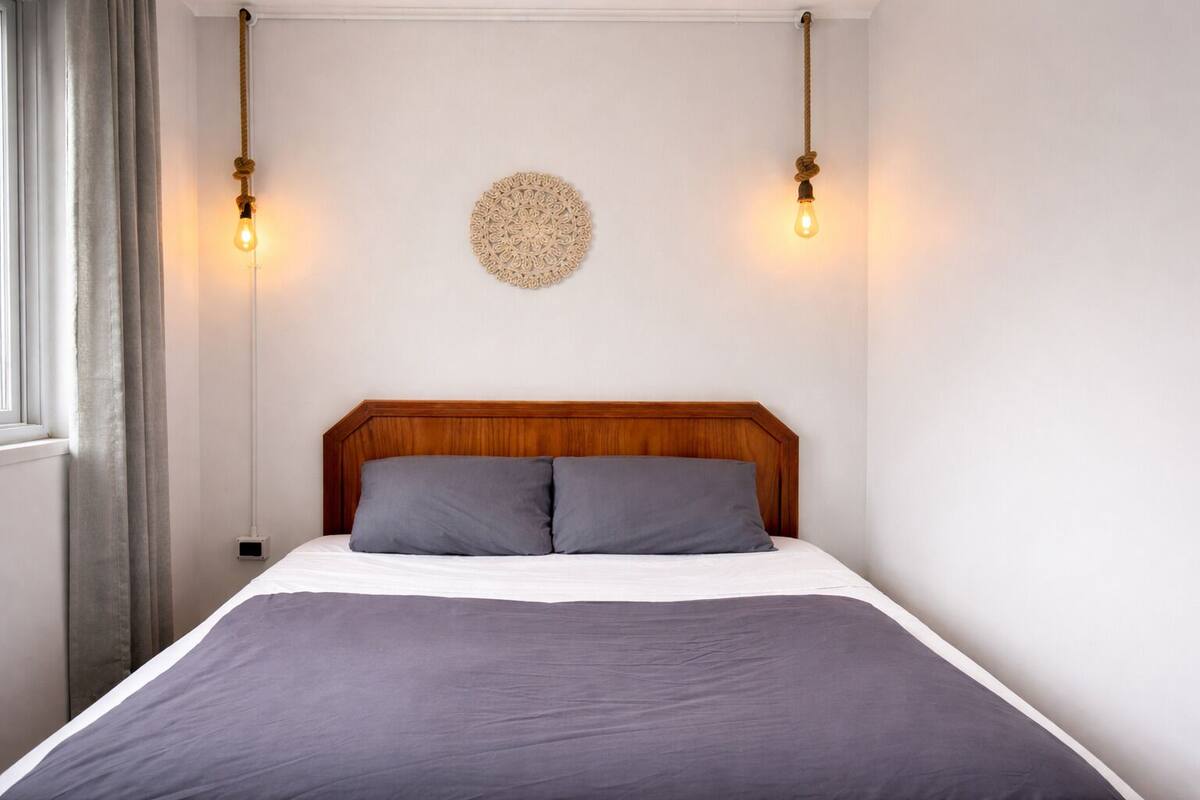 A bed with a wooden headboard, two bedside lamps, and a decorative wall piece.
