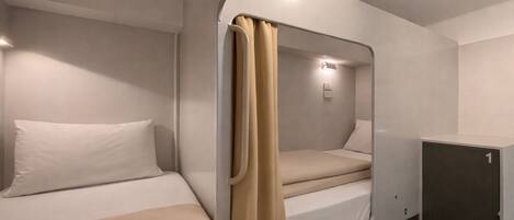 A compact, single-room cabin with a bunk bed, a small cabinet, and a curtain.