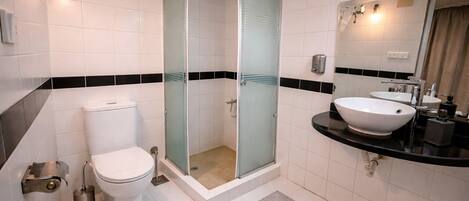 A bathroom with a toilet, a glass-enclosed shower, and a sink with a mirror.