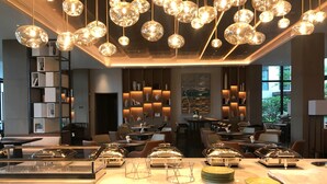 Um restaurante moderno com uma área de buffet central, diversas mesas de jantar e uma variedade de opções de assento.
