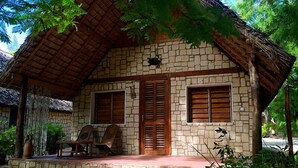 A stone house with a thatched roof, two windows with shutters, and a porch with chairs. - Bamboo Club (Ifaty)