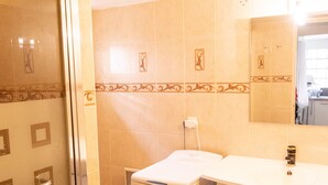 Ein Badezimmer mit Duschkabine aus Glas, einem weißen Waschbecken und einer integrierten Waschmaschine.