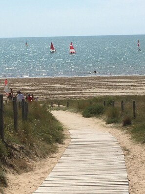 Una passerella in legno che conduce a una spiaggia sabbiosa con vista libera sull'oceano.
