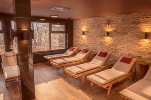 Un cuarto de spa con camastros de madera, una pared de piedra y un amplio ventanal.