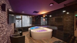 A modern spa room with a large bathtub, a massage chair, and a wooden floor. - Wellness Hotel Astra (Spindleruv Mlyn)