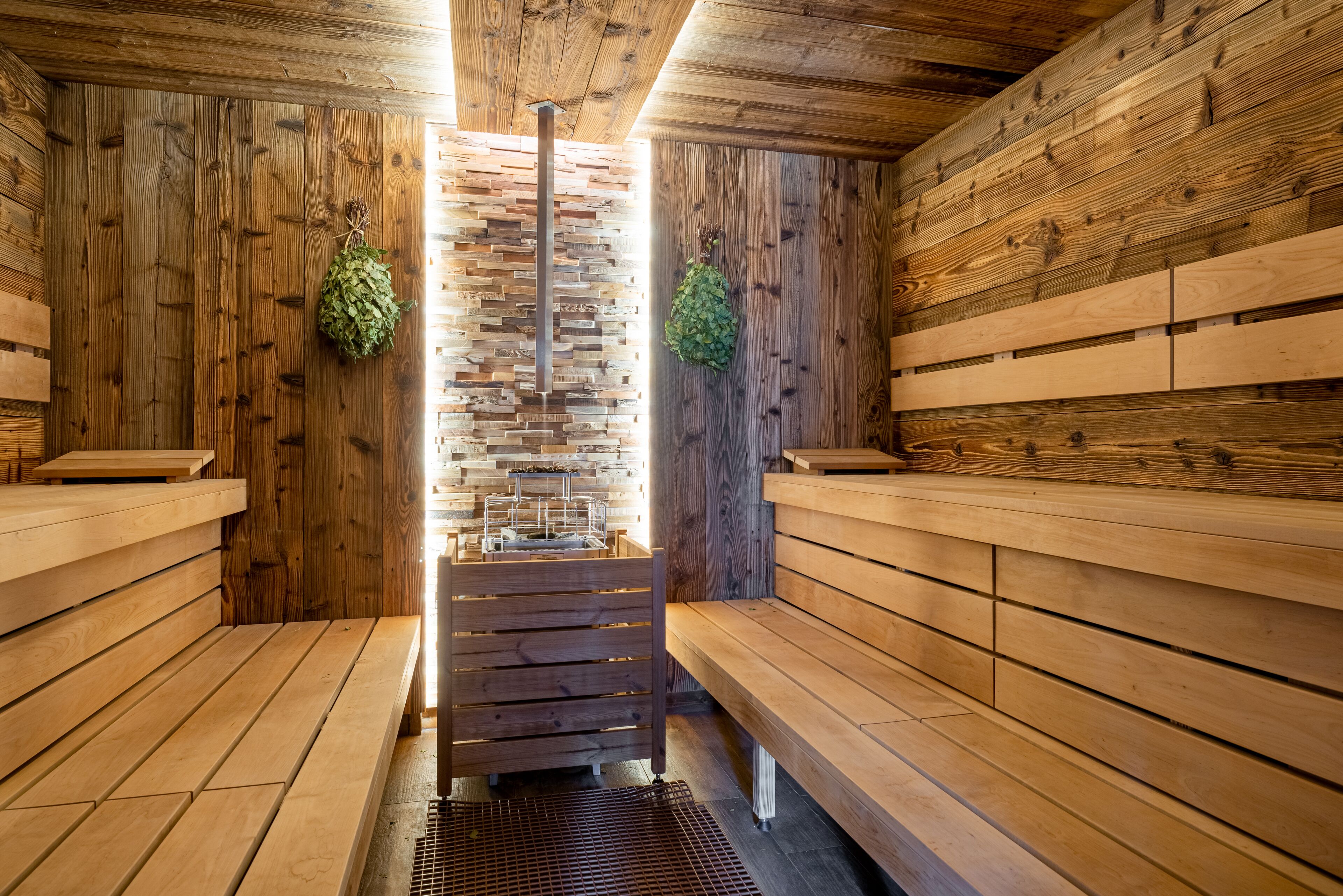 A sauna with wooden benches and a central bench with a sink.