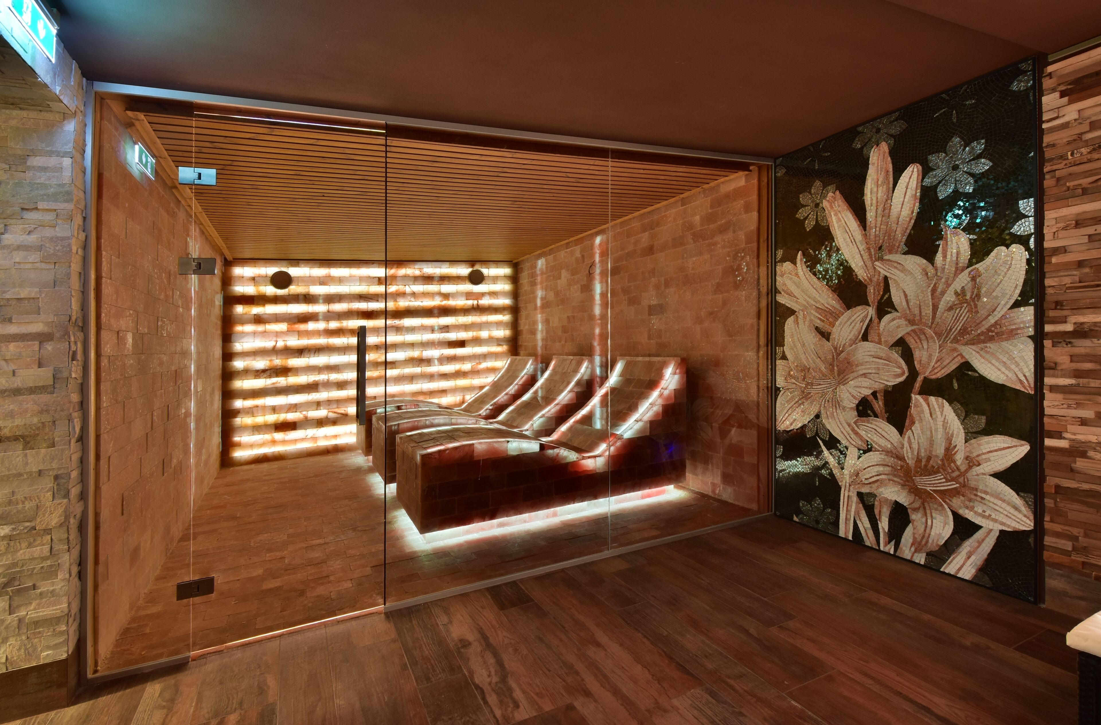 A modern spa room with a wooden bench, a large floral mural, and a slatted ceiling design.