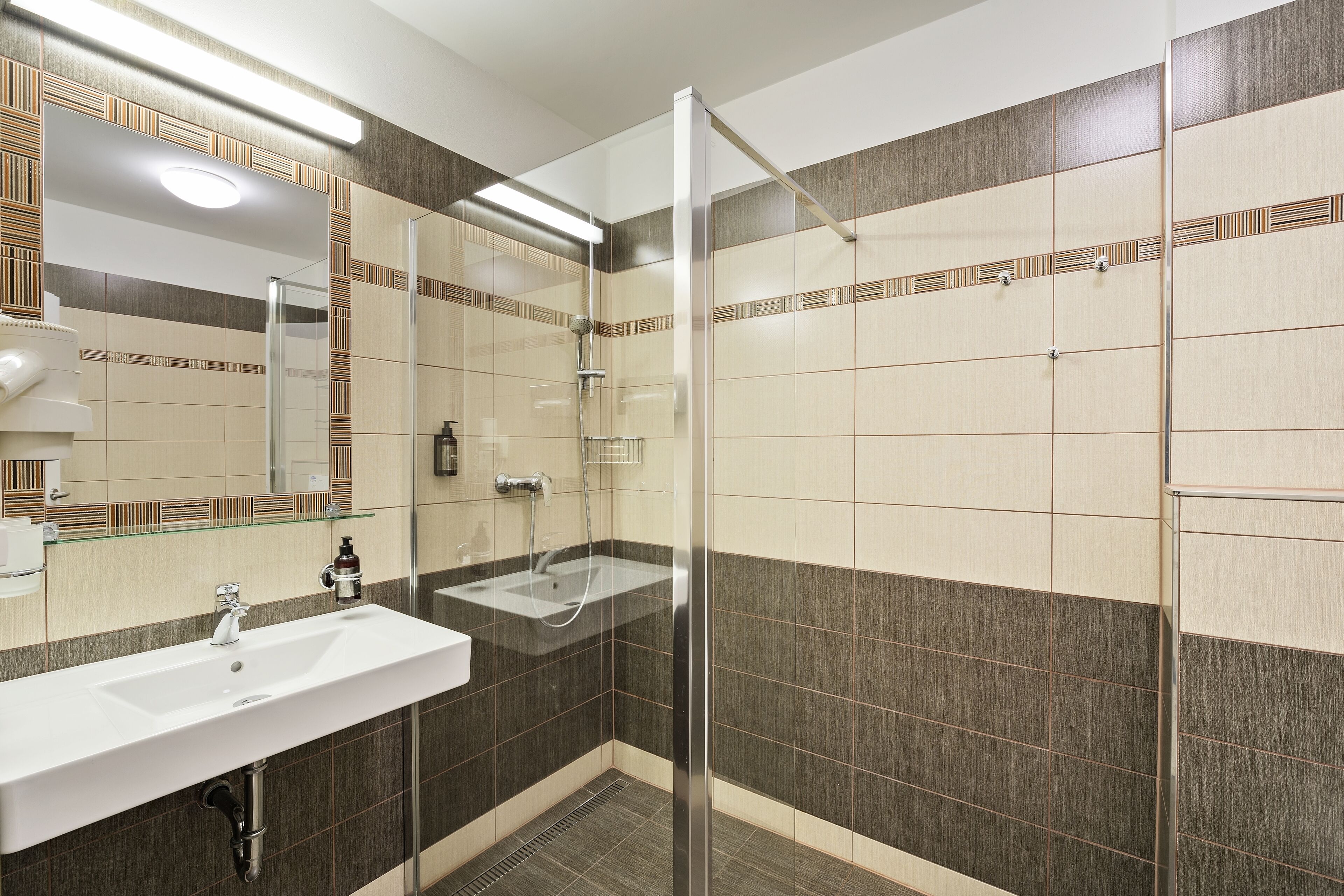 A modern bathroom with a glass shower enclosure, a sink with a mirror, and tiled walls.
