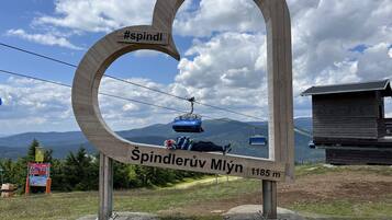 A wooden sign with a ski lift and mountains in the background.