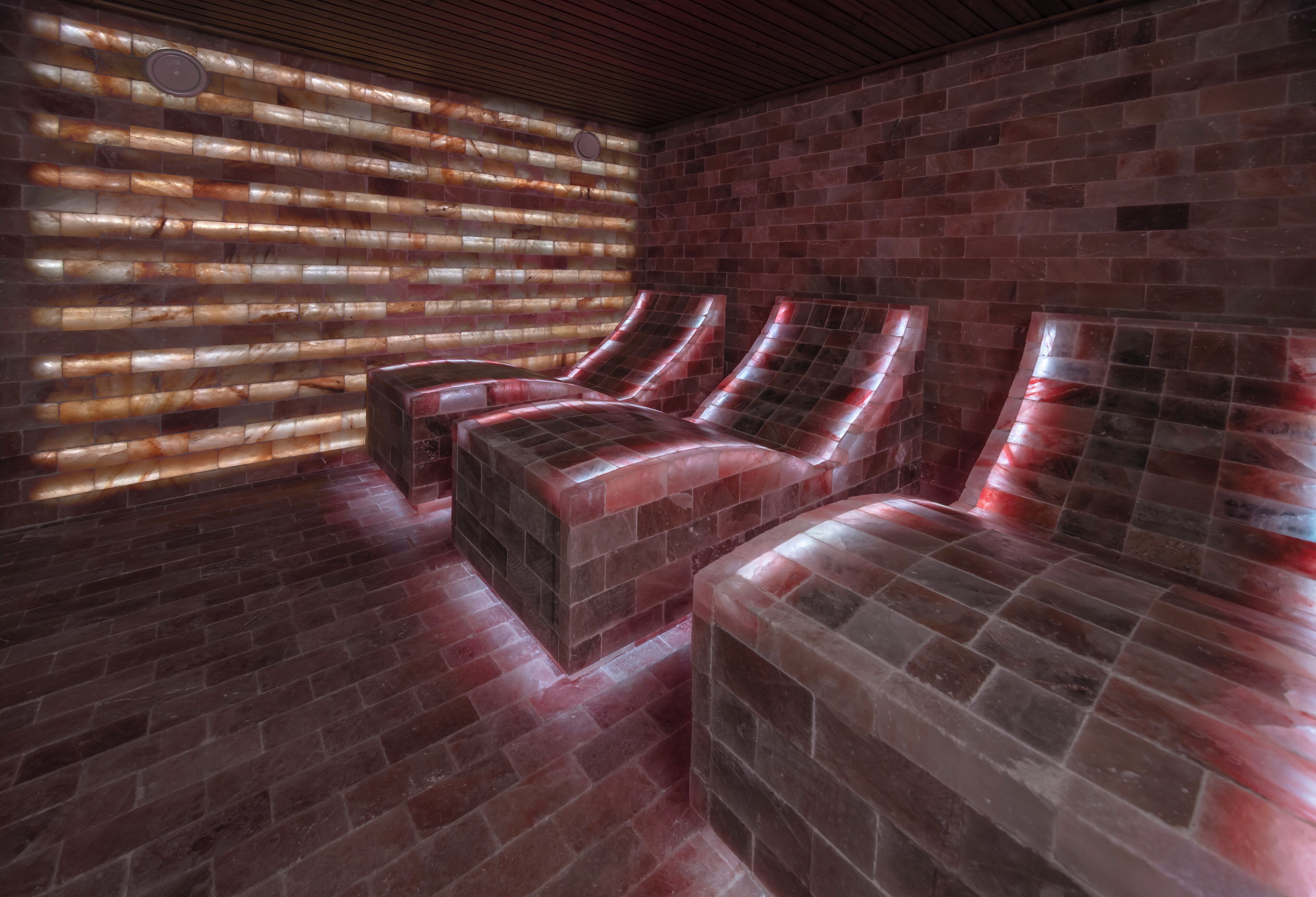 A spa room with a brick wall, a wooden ceiling, and a large window with blinds.