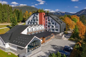 Un edificio moderno con un estacionamiento y montañas al fondo.