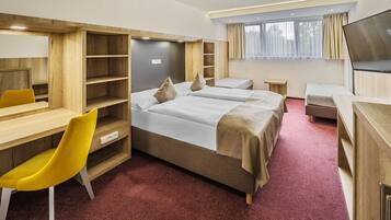 A hotel room with a bed, two bedside tables, a desk with a chair, a TV, and built-in shelving.