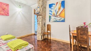 A room with a bed, a wooden chair, a dining table, and a stone pillar. - Apartment Old City 2 (Pula)