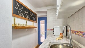 A kitchen with a stainless steel sink, a chalkboard with a message, a blue door, and a tiled backsplash. - Apartment Old City 2 (Pula)
