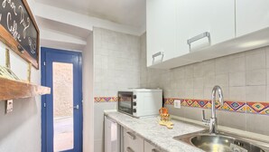 A compact kitchen with a blue door, a microwave, a sink, and a small cabinet. - Apartment Old City 2 (Pula)
