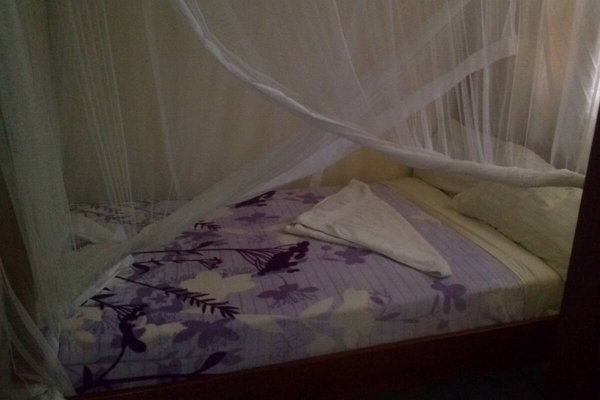 Una cama con una colcha estampada con motivos florales, una almohada blanca y un dosel.