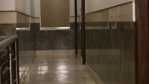 A corridor with a marble floor, recessed lighting, and a glass door at the end. - Hotel Aangan Regency (Shimla)